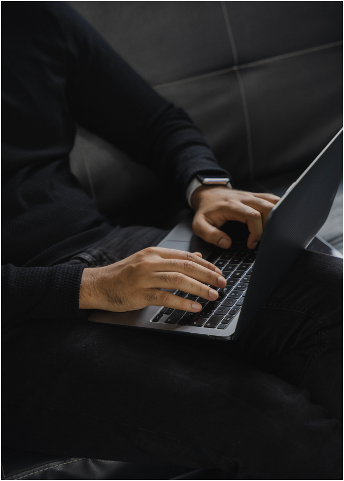 Mãos digitando em um notebook, em ambiente de trabalho escuro